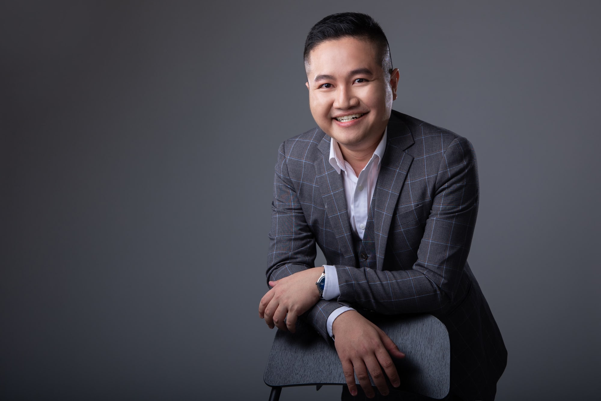 Kevin Lee, property advisor, smiling, leaning on a chair in a studio
