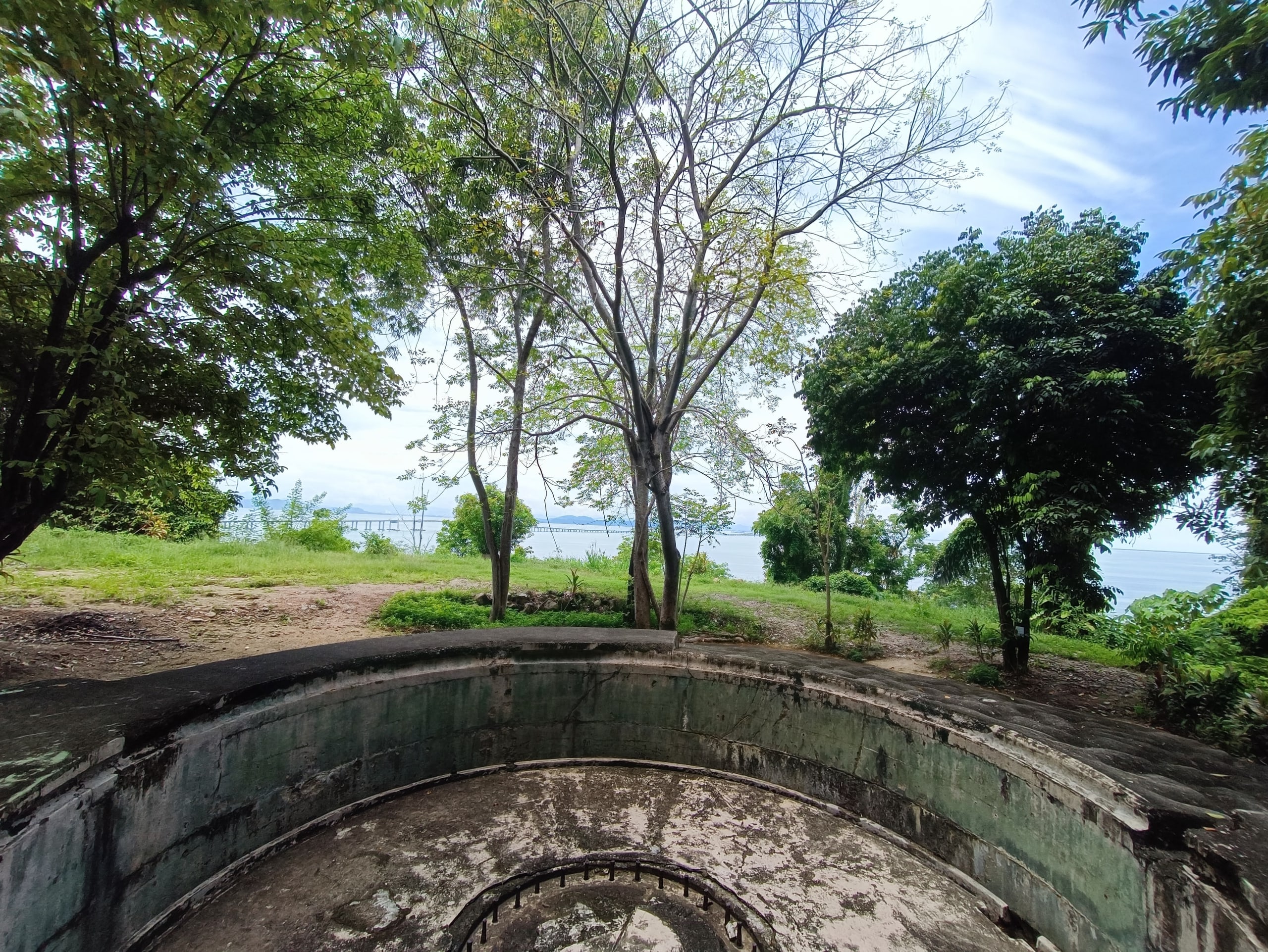 A circular concrete gun emplacement among trees at the Penang War Museum on Bukit Batu Maung